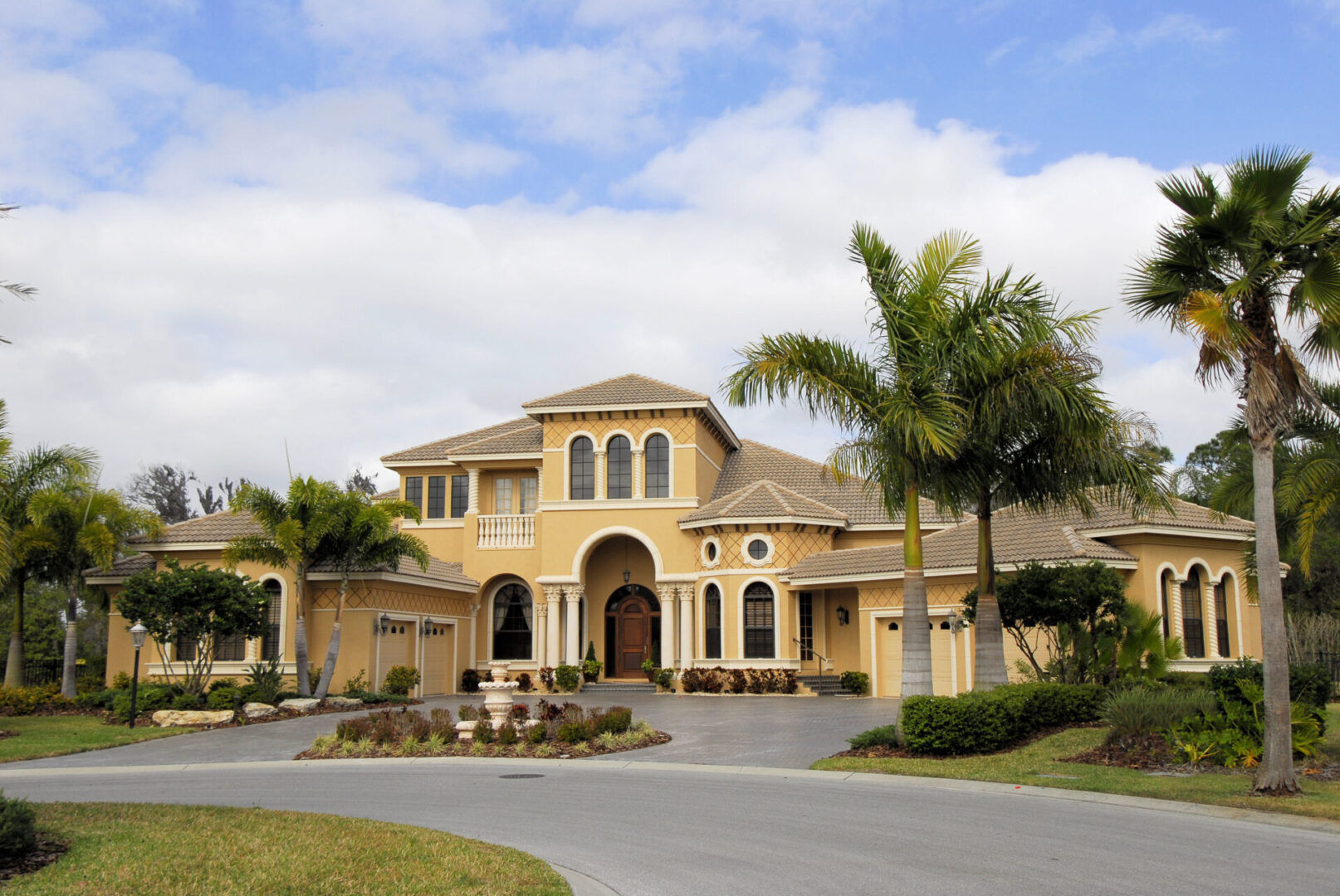 A large yellow house with palm trees in front of it.