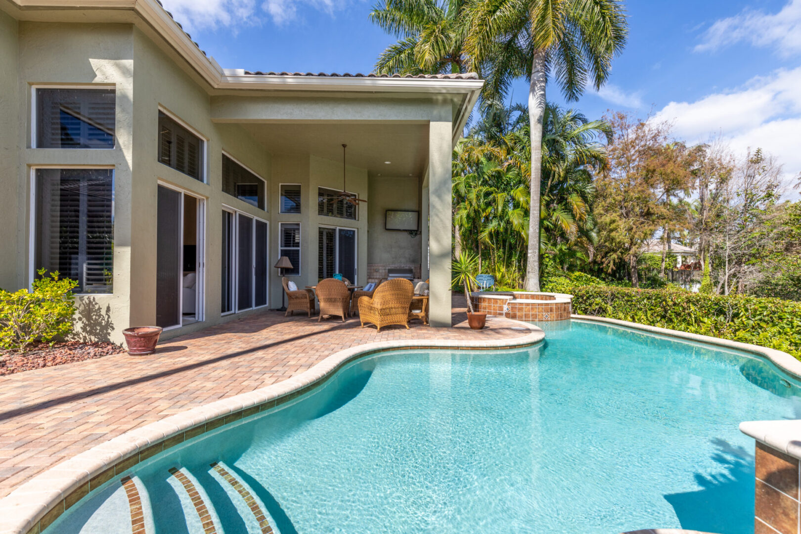 A pool with chairs and palm trees in the background.