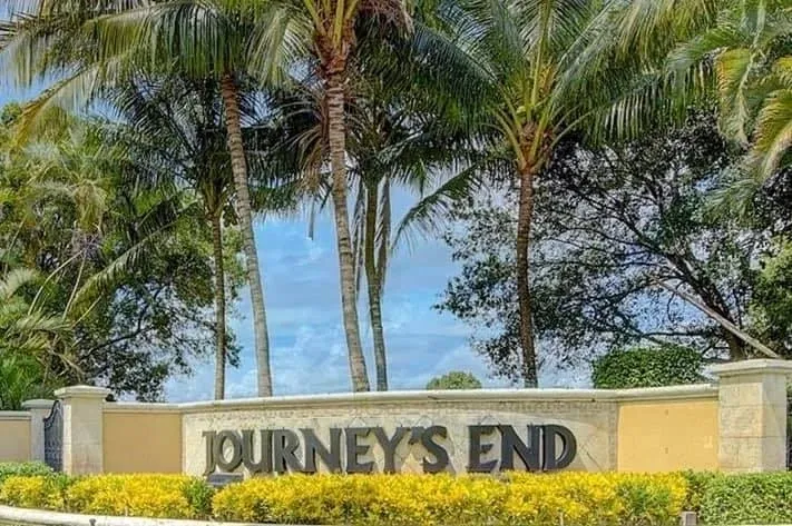 A sign that says journey 's end in front of some palm trees.