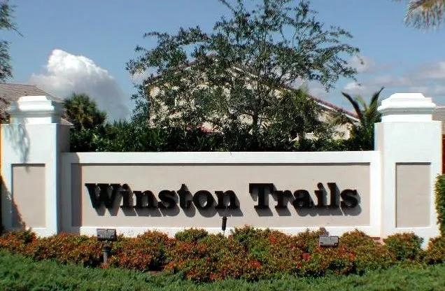 A sign that says winston trails in front of some bushes.