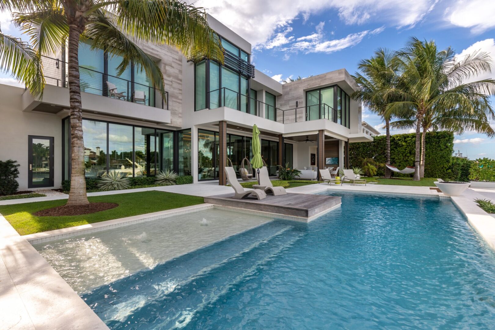 A large pool with chairs and palm trees in the background.